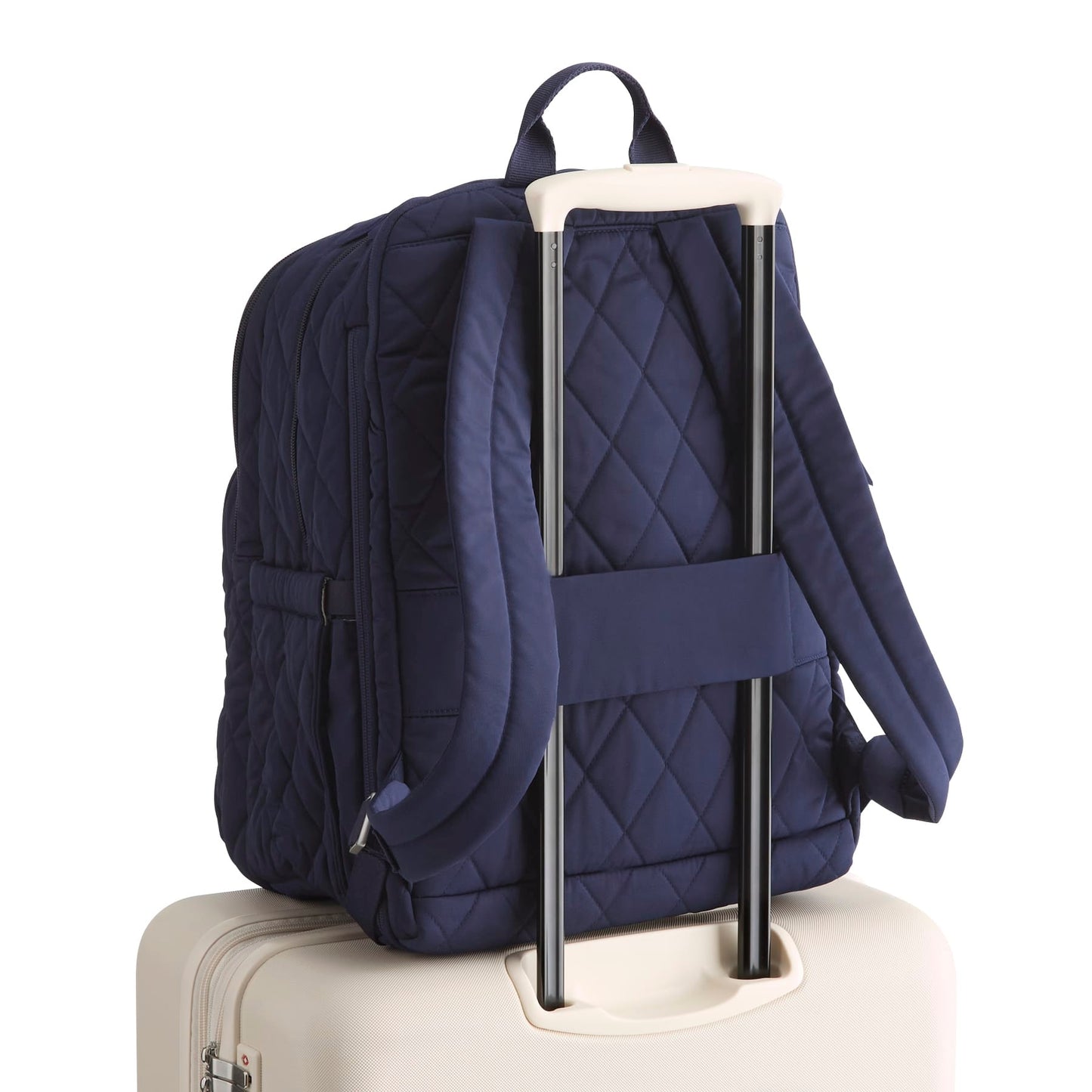Navy quilted backpack on a beige suitcase with a white background